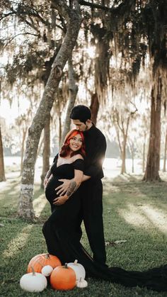 a pregnant woman hugging her husband in front of trees