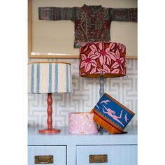 two lamps on top of a blue dresser next to a lamp shade and wallpaper