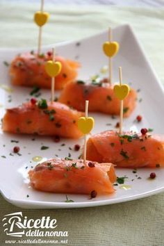 small appetizers with toothpicks are arranged on a white plate, ready to be eaten