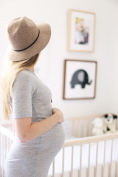 a woman with long blonde hair wearing a hat and looking at an elephant on the wall