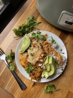 a white plate topped with rice covered in meat and veggies next to an air fryer