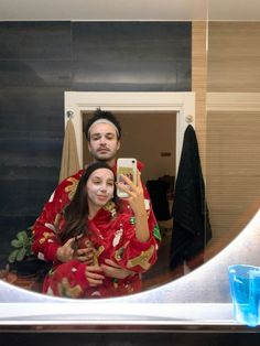 a man and woman taking a selfie in front of a mirror with blue water