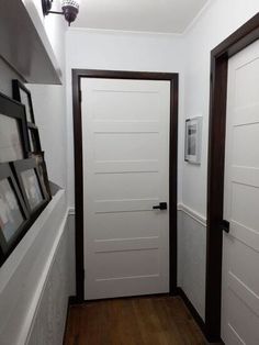 two doors are open in a white room with wood flooring and framed pictures on the wall