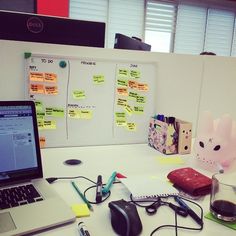 an office desk with a laptop computer, mouse and sticky notes on the whiteboard