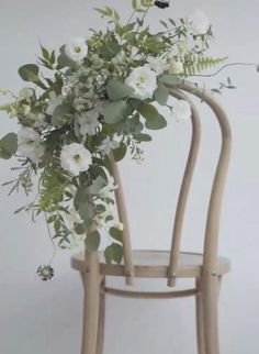 a wooden chair with flowers and greenery on it