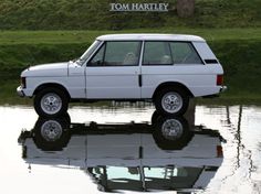 a white car is parked in the water near a sign that says tom hartley