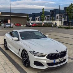 a white car parked in front of a building on the side of a road next to a parking lot