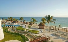 an aerial view of a beach resort and pool with palm trees in the foreground