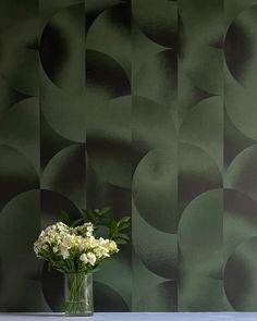 a vase filled with white flowers sitting on top of a table next to a wall