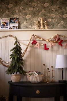 a christmas tree and decorations on a table in front of a wallpapered wall