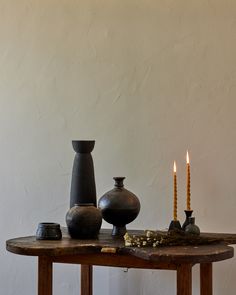 a table topped with vases and candles next to each other on top of a wooden table