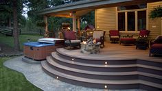 a patio with steps leading to a hot tub and fire pit in the back yard