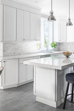 a large kitchen with white cabinets and marble counter tops, along with two bar stools