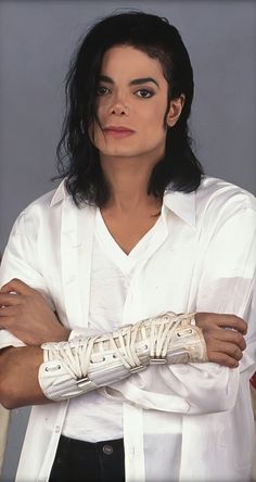 michael jackson in white shirt with arms crossed and hands wrapped around his chest, looking to the side