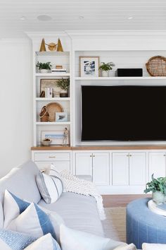 a living room filled with furniture and a flat screen tv on top of a white entertainment center