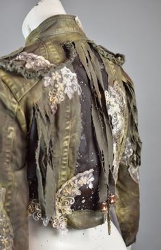 Crafted for the bold and the daring, this Avant-Garde Distressed Jacket is a sartorial masterpiece that fuses high fashion with urban grit. Its olive green and black panels are artfully distressed, evoking a rugged charm. Sheer, ghostly fabric drapes from the sleeves, adding a touch of the ethereal to your movements. This jacket is not just a garment; it's a statement, designed for the fashion-forward individual who commands attention and dares to defy the ordinary. Embrace the allure of unconventional beauty--make this jacket yours today and redefine your style! All of our clothes are handmade, which is why individual pieces may slightly differ from those shown in the photos. If you can't find your size or would like to customize this product according to your preferences, please don't he Clothing Inspired By Nature, Green Glamour Outfit, Desert Punk Fashion, New Age Fashion, Dragon Inspired Fashion, Eco Futurism Fashion, Olive Green And Black Outfit, Eco Punk Fashion, Biopunk Fashion