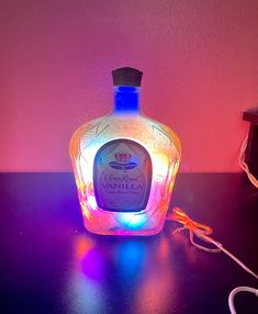 a lighted bottle sitting on top of a table next to a charger and cords