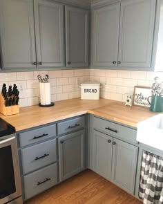 a kitchen with gray cabinets and white subway backsplash