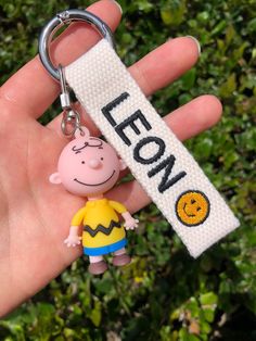 "It's easy to personalize your belongings with our adorable Charlie Brown name tag! A perfect way to personalize your purse, bag pack, keys, lunch bag, diaper bag, luggage, and many more! It comes with a personalized tag (made with high-quality cotton webbing), Charlie Brown figure, and a durable gate O Ring for easy clip on. You can choose either SMILE or SMILE FACE to be embroidered after your name. How to Order 1. Choose webbing color (drop down) 2. Choose thread color (drop down) 3. Write na Handmade White Keychains For Personalized Gifts, Handmade White Keychain For Personalized Gift, Customized White Keychains For Everyday Use, Cute White Keychains For Everyday Use, Custom Name White Keychains For Everyday Use, Cute Customized Keychains For Personalized Gift, Customized White Keychains For Personalized Gift, Customizable Rectangular Keychain For Everyday Use, Custom Name White Keychain