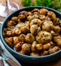 a blue bowl filled with cooked potatoes on top of a wooden table next to silverware