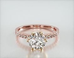 a yellow gold engagement ring with diamonds on the band and a round cut diamond in the center