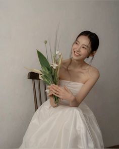 a woman sitting on a chair holding a bouquet of flowers