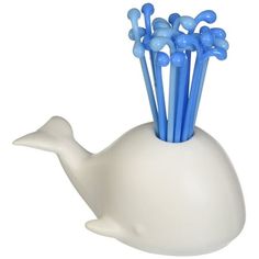 a white whale shaped vase with blue sticks sticking out of it's back end