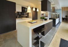 a modern kitchen with an island in the middle and bar stools at the end