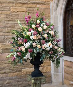 a vase filled with lots of flowers next to a building