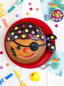 a cake decorated to look like a clown on a red plate with confetti