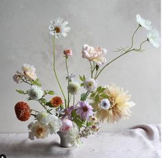 a vase filled with lots of different colored flowers on top of a white table cloth