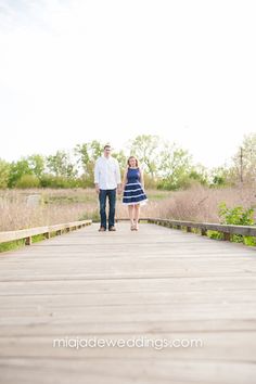 a man and woman holding hands walking across a bridge