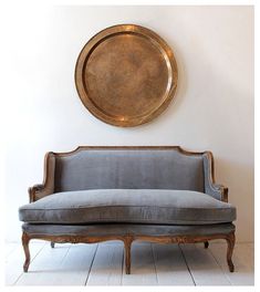 a couch sitting in front of a gold plate on the wall