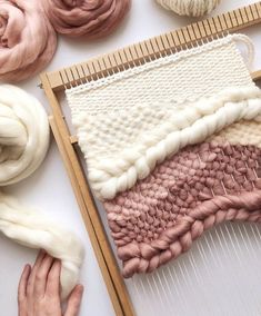 someone is weaving yarn on a loom with their hands and knitting needles next to it