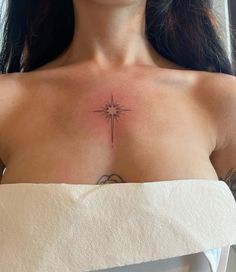 a woman's chest with a star tattoo on her left side and the cross in the middle