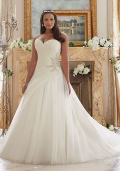 a woman in a wedding dress standing next to a fireplace