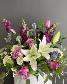 a white vase filled with lots of purple and white flowers