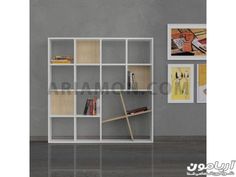 a white book shelf with books and pictures on the wall