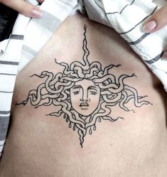 a woman's stomach with a tattoo design on the side and her face in the center