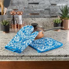 pots and pans sitting on a kitchen counter with blue towels in front of them