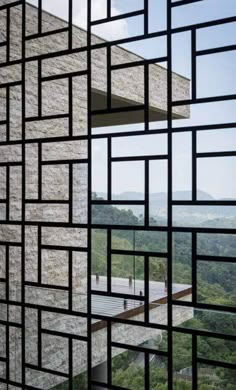 the view through an open window at a building with mountains in the background and trees