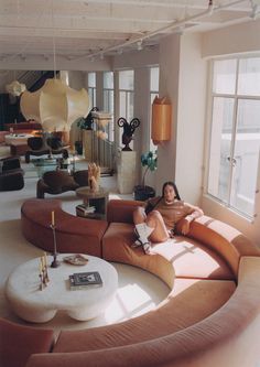 a woman sitting on top of a couch in a living room next to a window