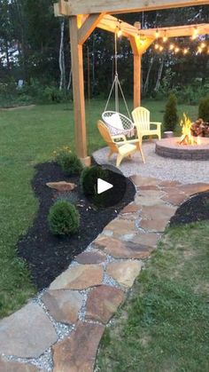 a patio with a swing chair and fire pit in the back yard, surrounded by landscaping