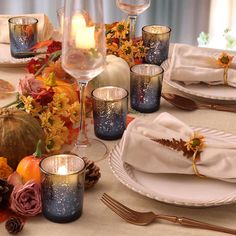 the table is set with candles, plates and napkins