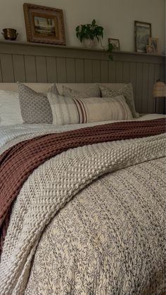 a bed with many pillows and blankets on it's headboard in a bedroom