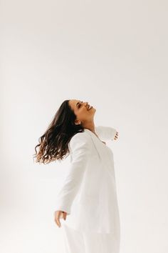 a woman in white is standing with her hands on her neck and looking up at the sky