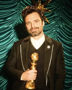 a man in a tuxedo holding an oscar award for best performance by an actor