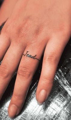 a person's hand with a small tattoo on their left thumb and the word love written in cursive writing