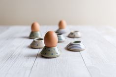 several ceramic eggs sitting on top of each other in the middle of a white table