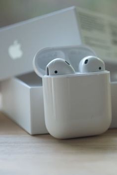 two apple airpods sitting in front of an open box